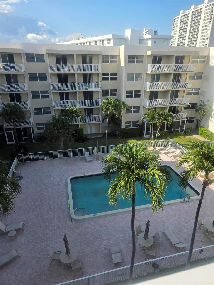 An elevated view of a swimming pool surrounded by a patio and a multi-story building — 2929 S Ocean Boulevard # 5060, Boca Raton FL 33432, BOCA RATON, FL