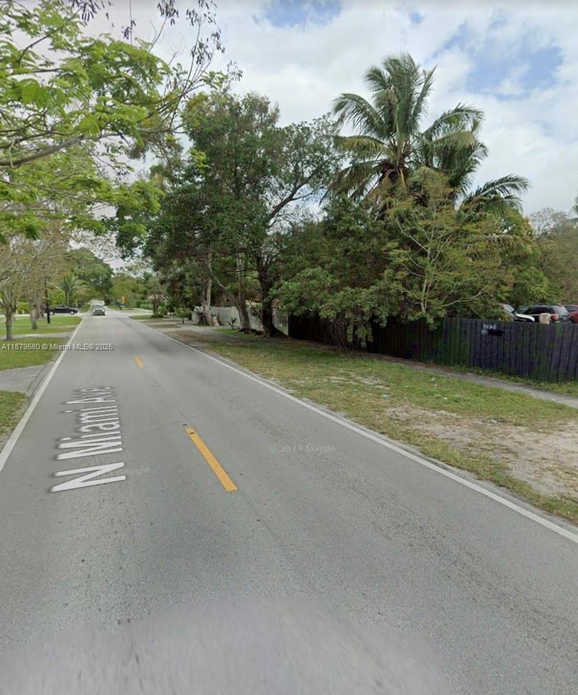 A paved road runs through a residential area with trees, a fence, and parked cars — 15505 N Miami Ave, Miami FL 33169, MIAMI, FL