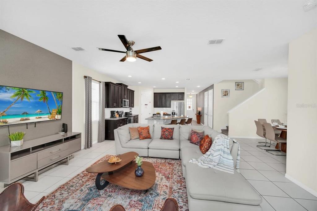 An open-concept living room features a sectional sofa, a coffee table, and a kitchen area — 9009 EGRET MILLS TERRACE, KISSIMMEE, FL