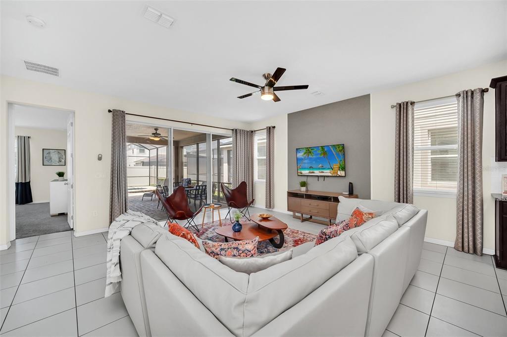A living room with tile floors, a sectional sofa, and a sliding door to a patio — 9009 EGRET MILLS TERRACE, KISSIMMEE, FL