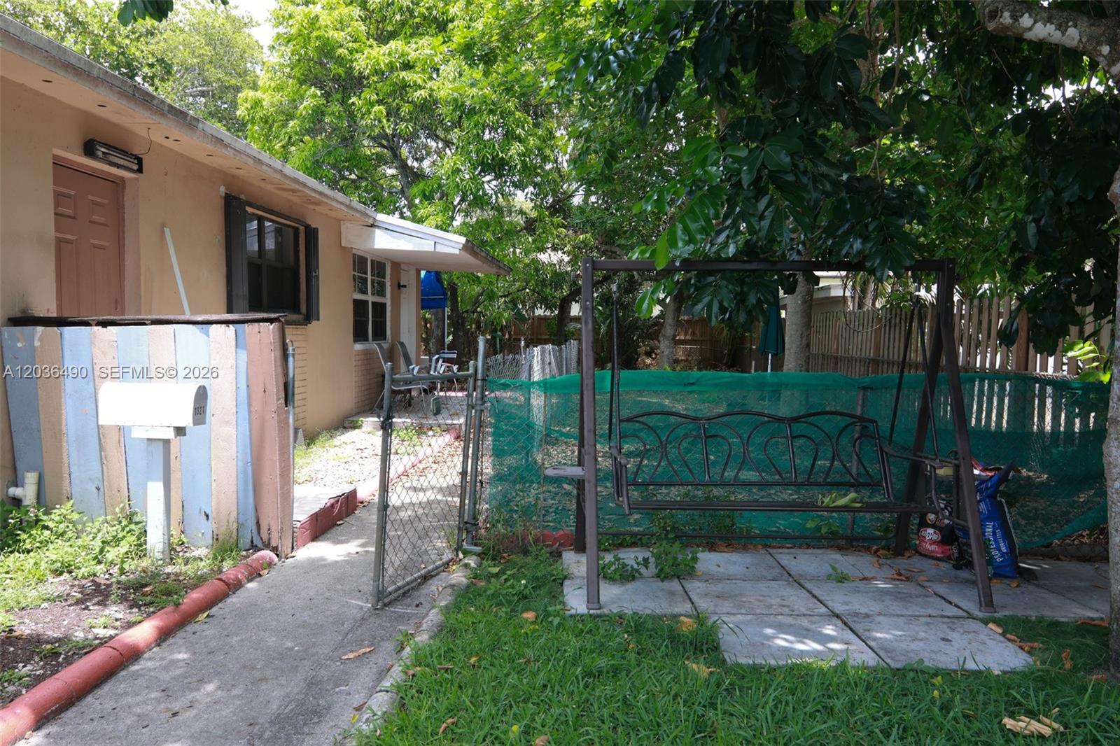 A metal swing sits on a concrete patio next to a house with a fence — 1321 N 58th Ave # 1321, Hollywood FL 33021, HOLLYWOOD, FL
