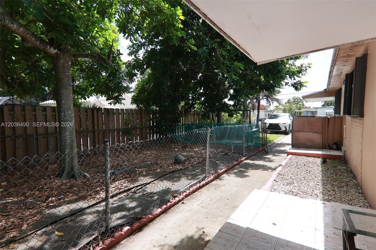 A concrete patio area features a chain-link fence, a tree, and a gravel section — 1321 N 58th Ave # 1321, Hollywood FL 33021, HOLLYWOOD, FL