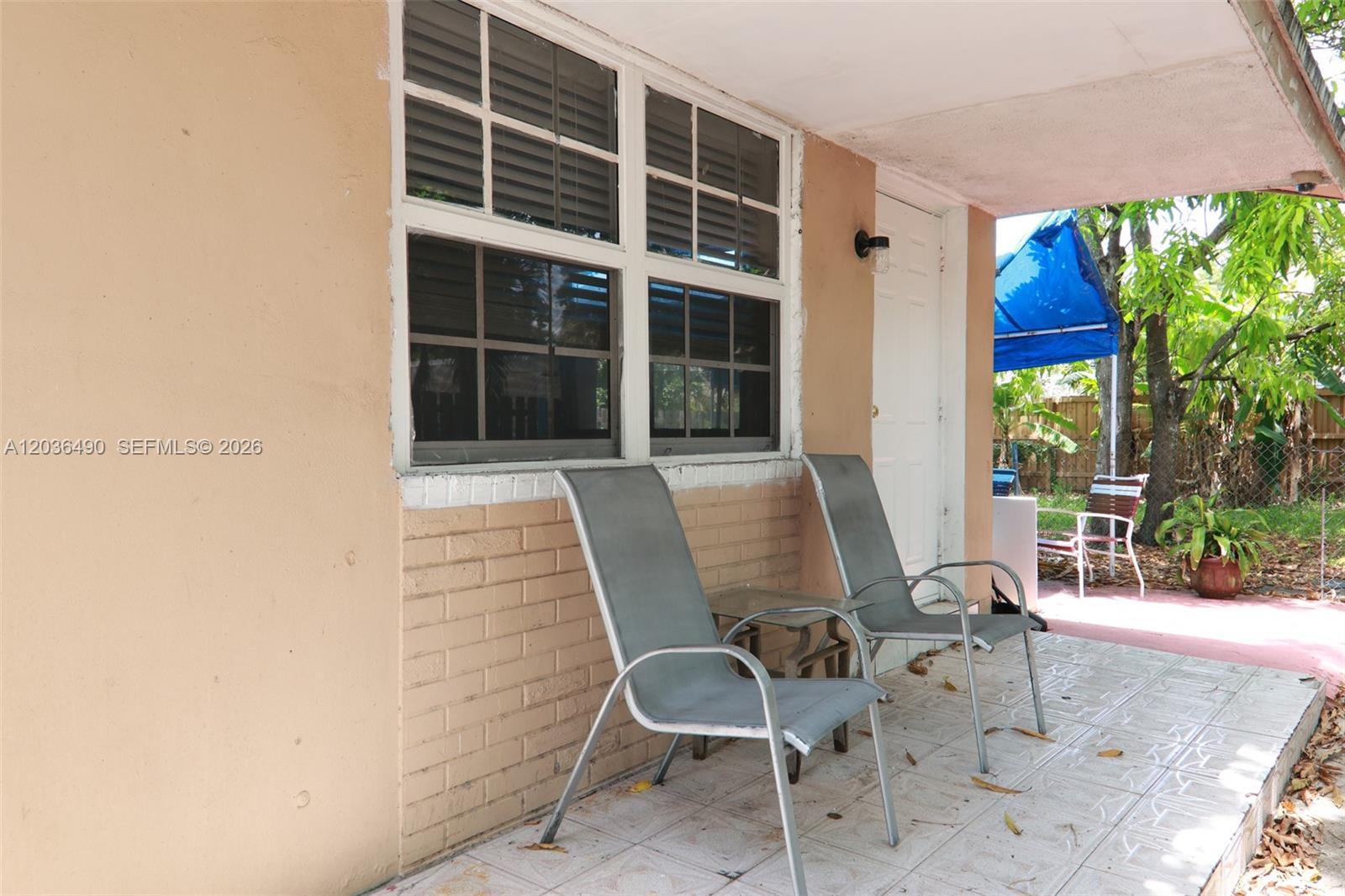 A covered patio features two metal chairs, a brick base, and a white door — 1321 N 58th Ave # 1321, Hollywood FL 33021, HOLLYWOOD, FL