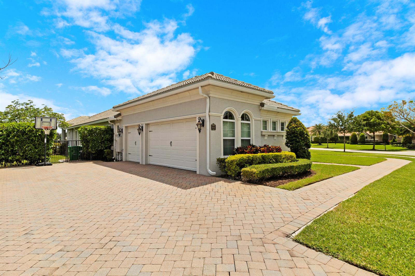 A paved driveway leads to a light-colored house with a two-car garage and landscaping — 4830 W Sterling Ranch Circle, Davie FL 33314, DAVIE, FL