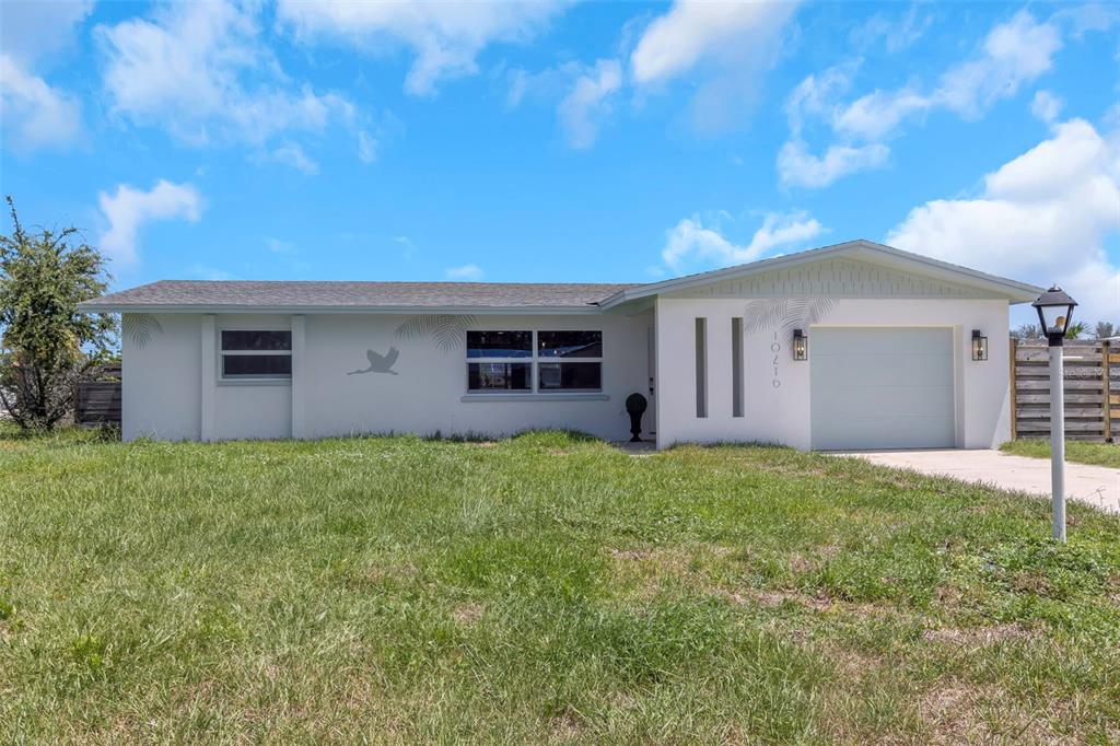 A single-story house with a white exterior, a garage, and a large front lawn — 10216 SPOONBILL ROAD E, BRADENTON, FL