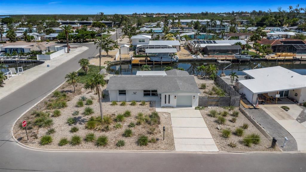 An aerial view shows a single-story house with a gravel yard and a canal behind — 10216 SPOONBILL ROAD E, BRADENTON, FL