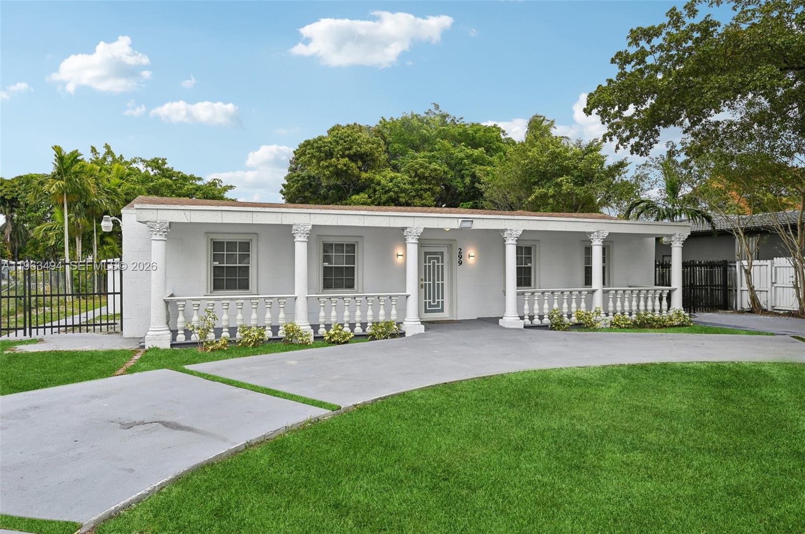 A single-story white house features a covered porch with decorative columns and a balustrade railing — 299 S Biscayne River Dr, Miami FL 33169, MIAMI, FL