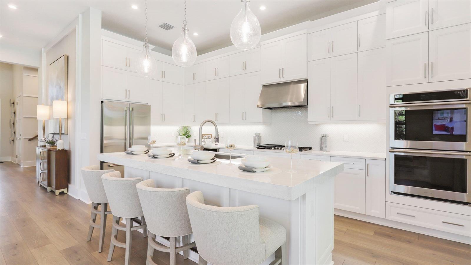 A bright kitchen features white cabinetry, a large quartz island, and stainless steel appliances — 1891 SE Royale Preserve Way, Stuart FL 34997, STUART, FL