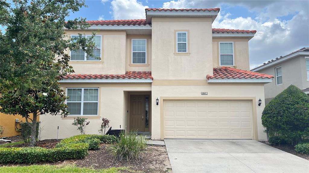 A two-story stucco house features a tile roof, a two-car garage, and a front entrance — 6041 BROAD OAK DRIVE, DAVENPORT, FL