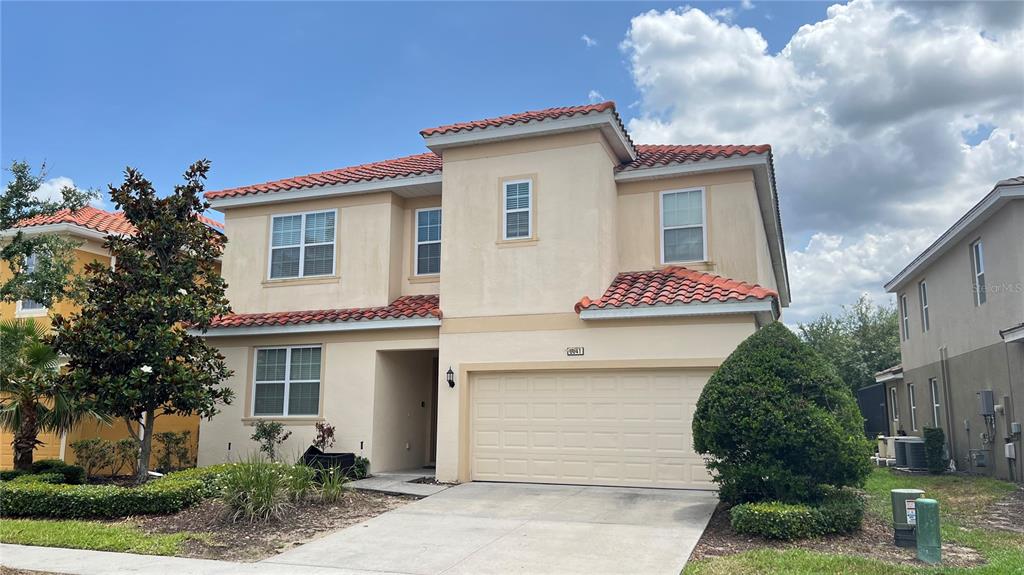 A two-story stucco house features a red tile roof and an attached two-car garage — 6041 BROAD OAK DRIVE, DAVENPORT, FL
