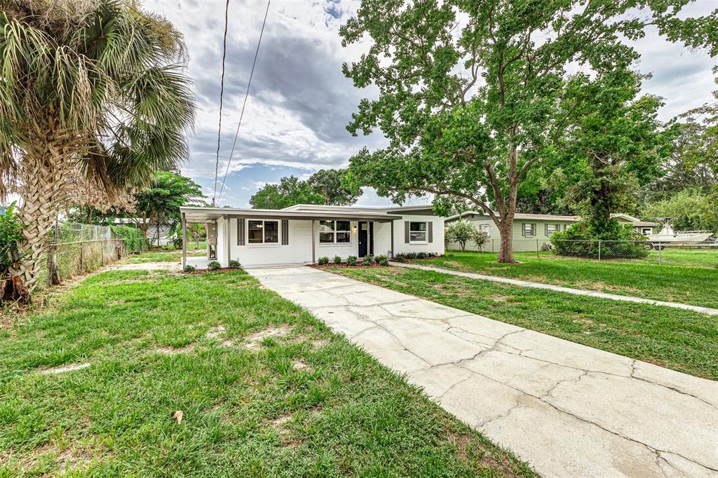 A kitchen with white cabinets and a breakfast bar opens into a living area — 526 VICTORIA BOULEVARD, AUBURNDALE, FL