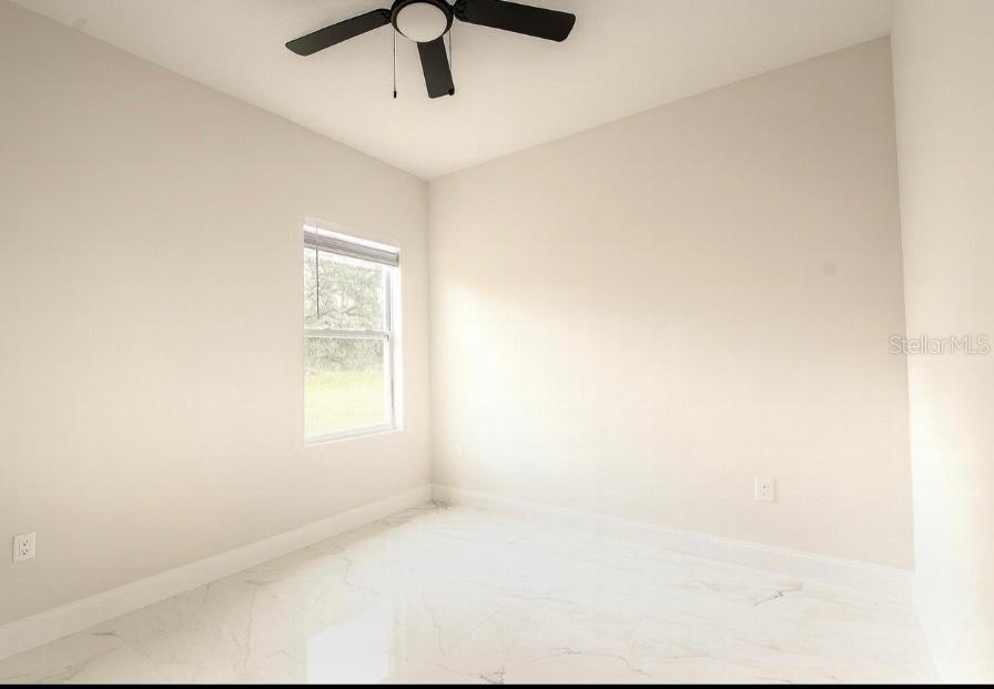 A bedroom with light-colored walls, a ceiling fan, and white marble-look tile flooring — 603 AMAZON PLACE, KISSIMMEE, FL