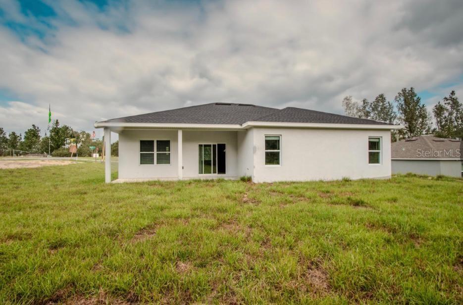 The rear exterior of a single-story house with a covered patio and a grassy yard — 603 AMAZON PLACE, KISSIMMEE, FL