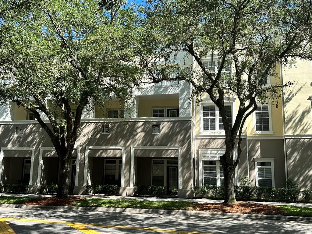 A multi-story residential building exterior with balconies, large windows, and mature trees in front — 729 CELEBRATION AVENUE UNIT 729, KISSIMMEE, FL