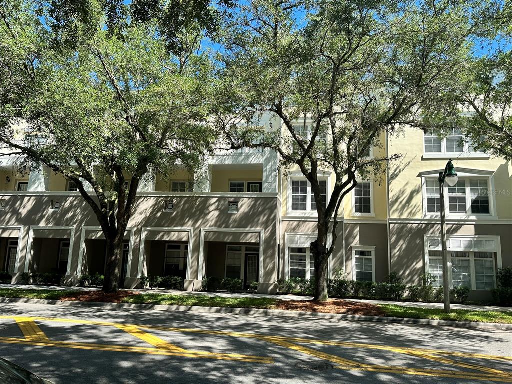 An elevated view looks down at a street with parked cars and storefronts under trees — 729 CELEBRATION AVENUE UNIT 729, KISSIMMEE, FL