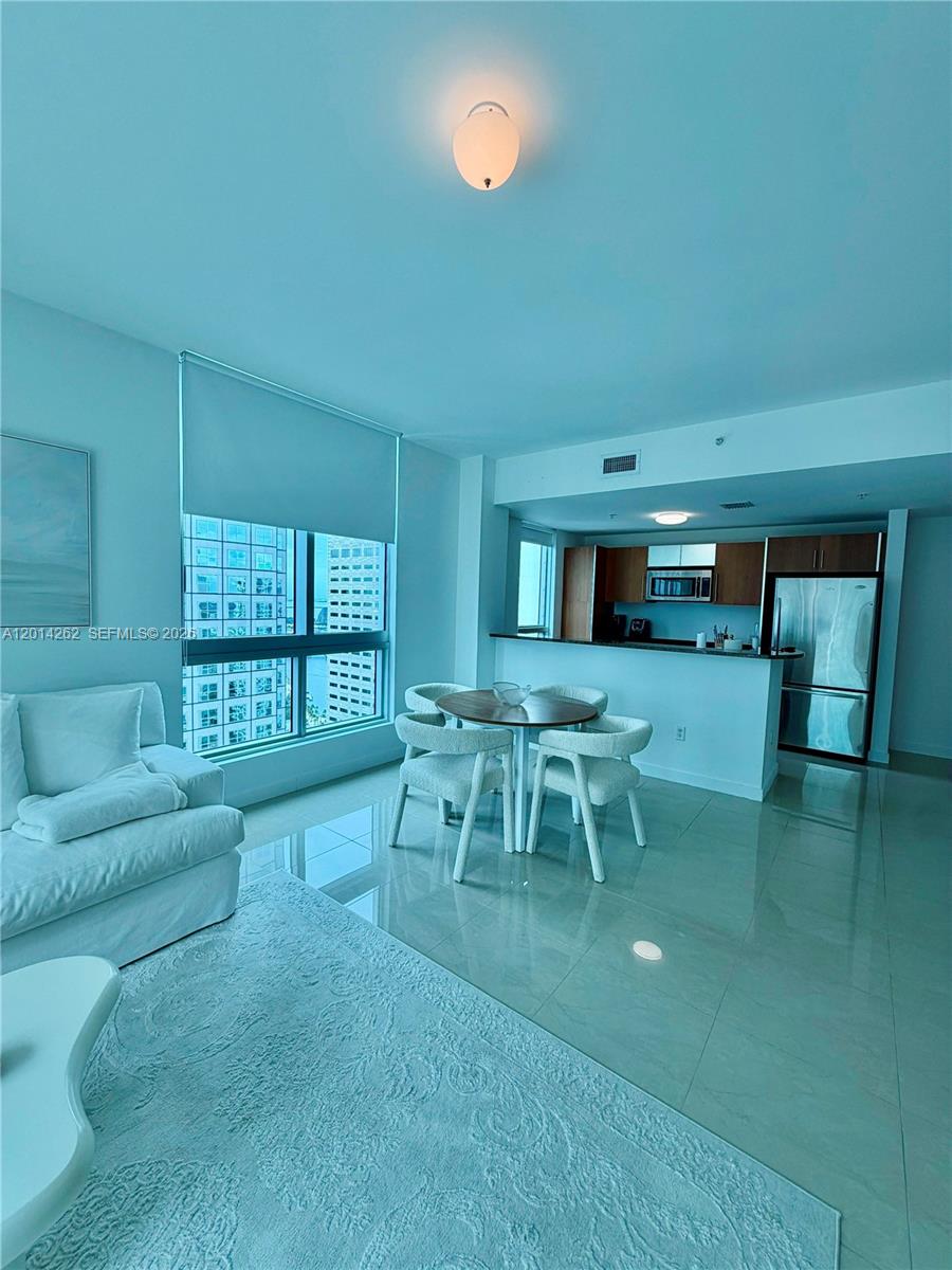 A living room and dining area with tile floors, a kitchen counter, and large windows — 300 S Biscayne Blvd # 3701, Miami FL 33131, MIAMI, FL