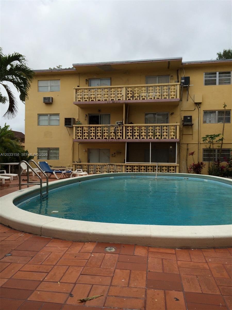 A three-story yellow apartment building overlooks a curved outdoor swimming pool — 2441 NW 13 ST # 77, Miami FL 33125, MIAMI, FL