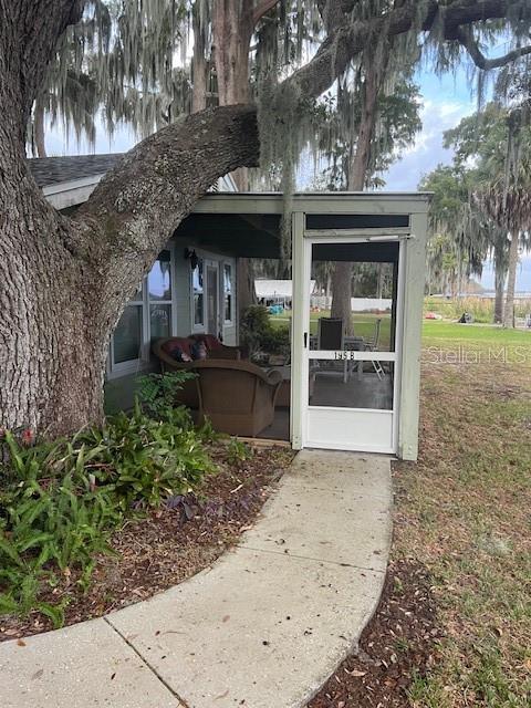 A concrete walkway leads to a screened-in porch entrance beneath a large, moss-draped oak tree — 195 MAE STREET UNIT B, EUSTIS, FL