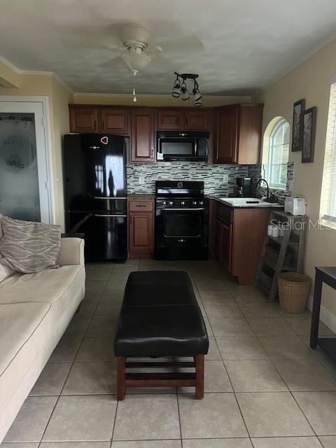 A kitchen with dark wood cabinets and black appliances is adjacent to a living area — 195 MAE STREET UNIT B, EUSTIS, FL