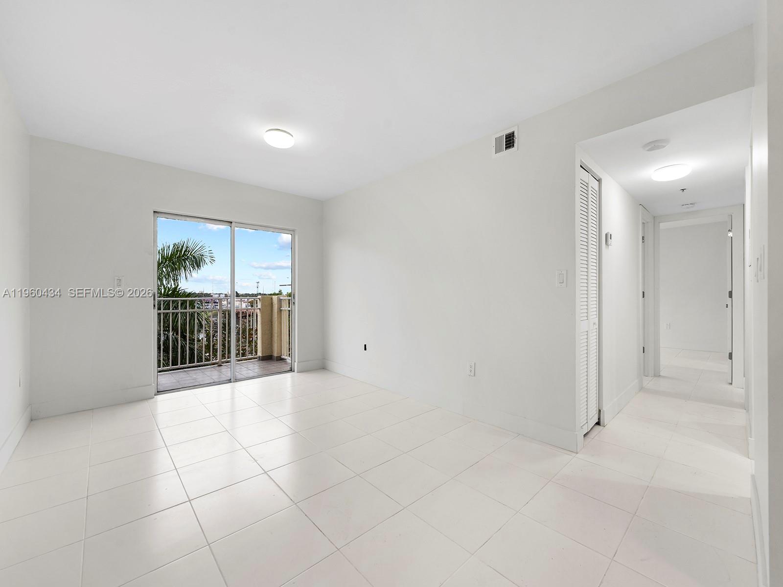 A bright, empty room with white tile floors, a sliding glass door, and a balcony — 1750 NW 27th Ave # 0, Miami FL 33125, MIAMI, FL