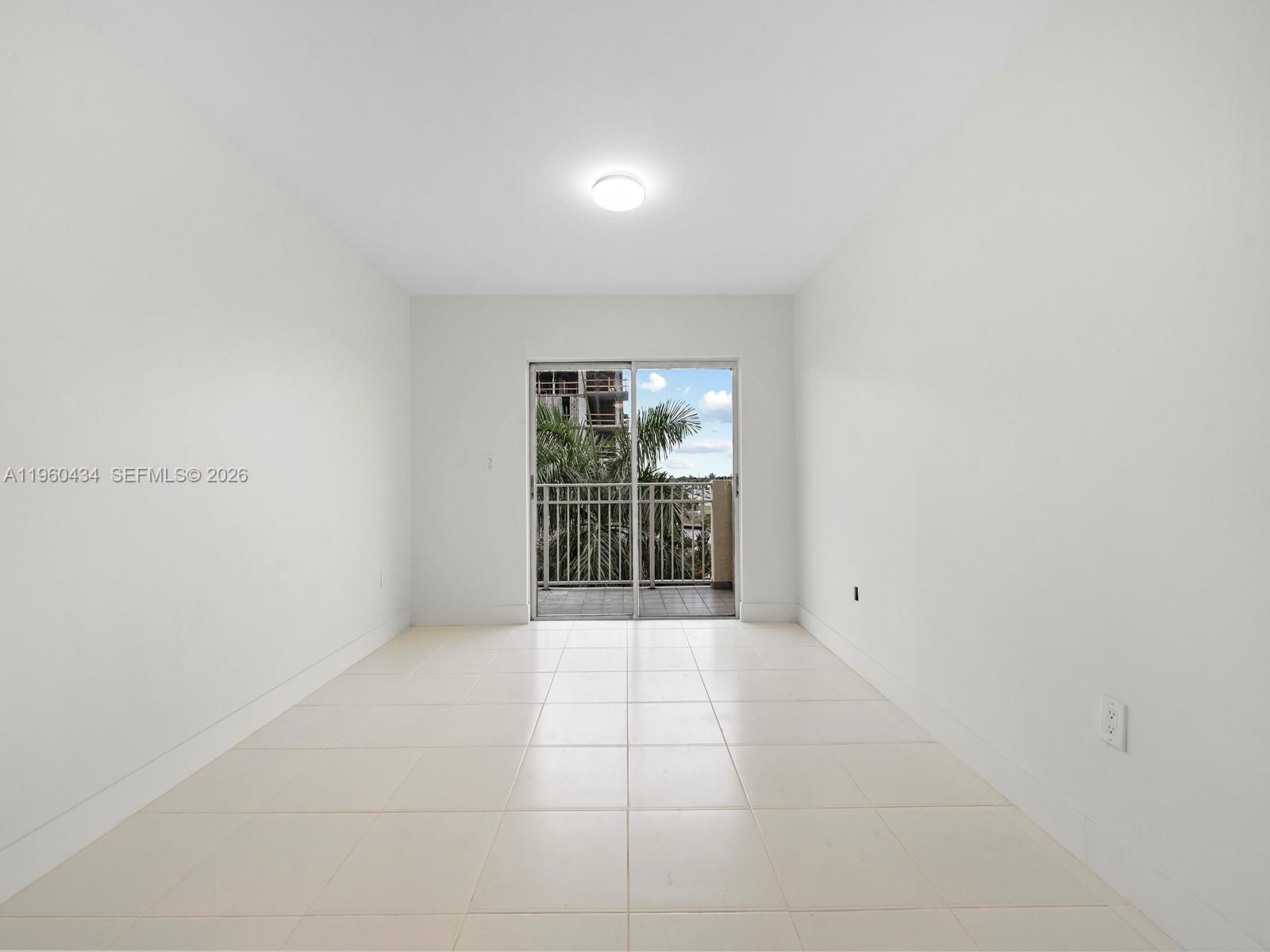An empty room with white walls, tiled floors, and a sliding glass door to a balcony — 1750 NW 27th Ave # 0, Miami FL 33125, MIAMI, FL