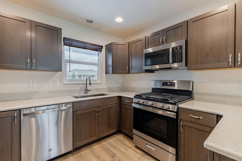 A kitchen with dark wood cabinets, stainless steel appliances, and light-colored speckled countertops — 7462 SAVANNA DRIVE, THE VILLAGES, FL