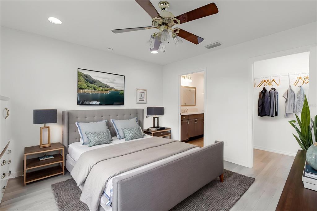 A bedroom features a gray upholstered bed, matching nightstands, a ceiling fan, and an attached closet — 7462 SAVANNA DRIVE, THE VILLAGES, FL