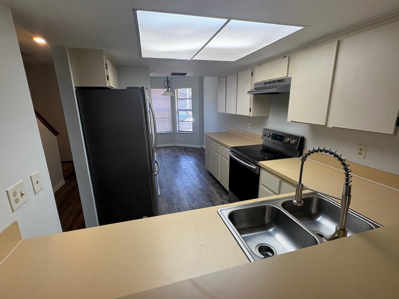 A kitchen features light-colored cabinets, tan countertops, stainless steel appliances, and a double-basin sink — 1838 Foxhall Circle, Kissimmee FL 34741, KISSIMMEE, FL