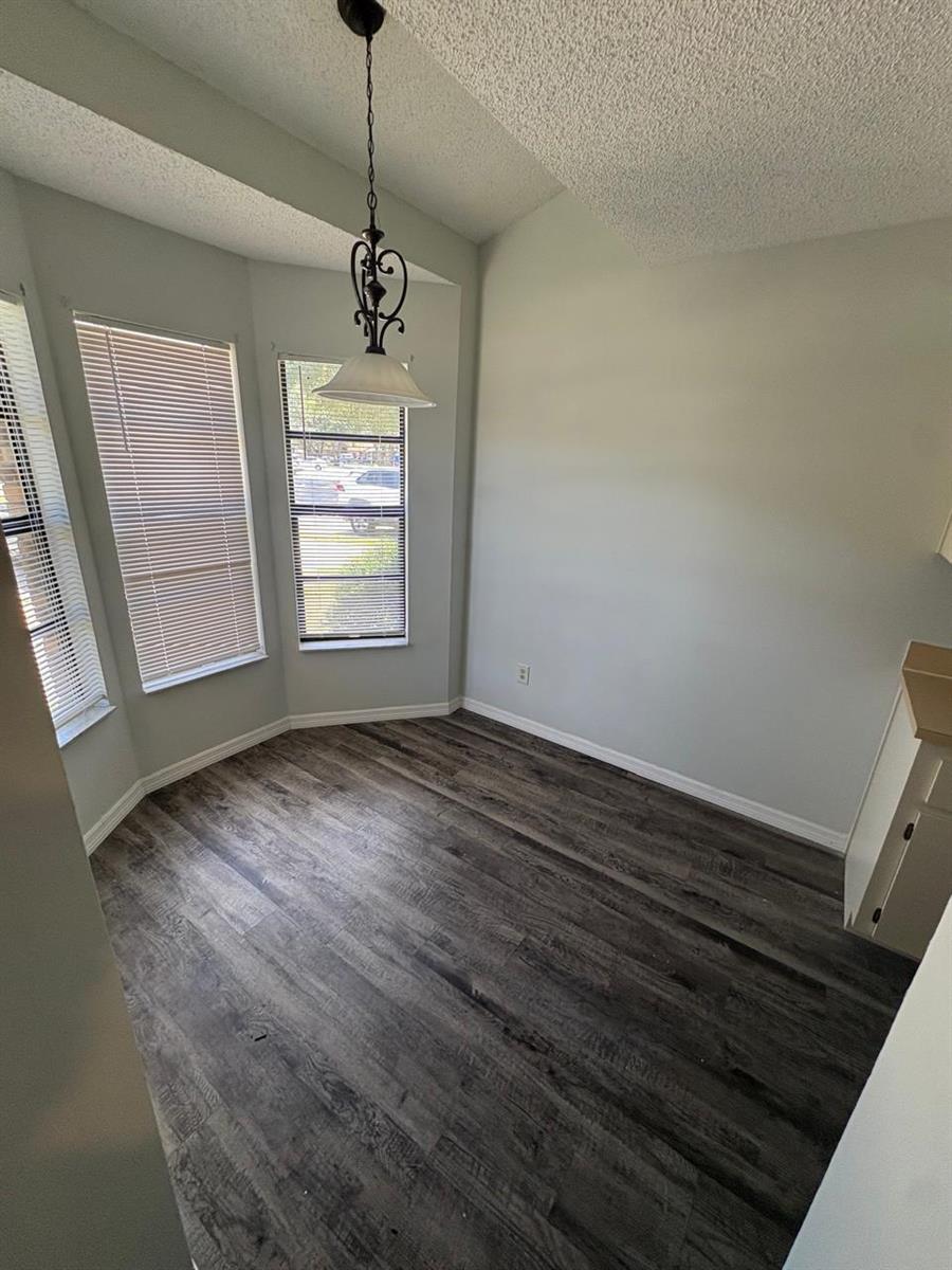 A dining area with wood-look flooring, a bay window, and a hanging pendant light fixture — 1838 Foxhall Circle, Kissimmee FL 34741, KISSIMMEE, FL