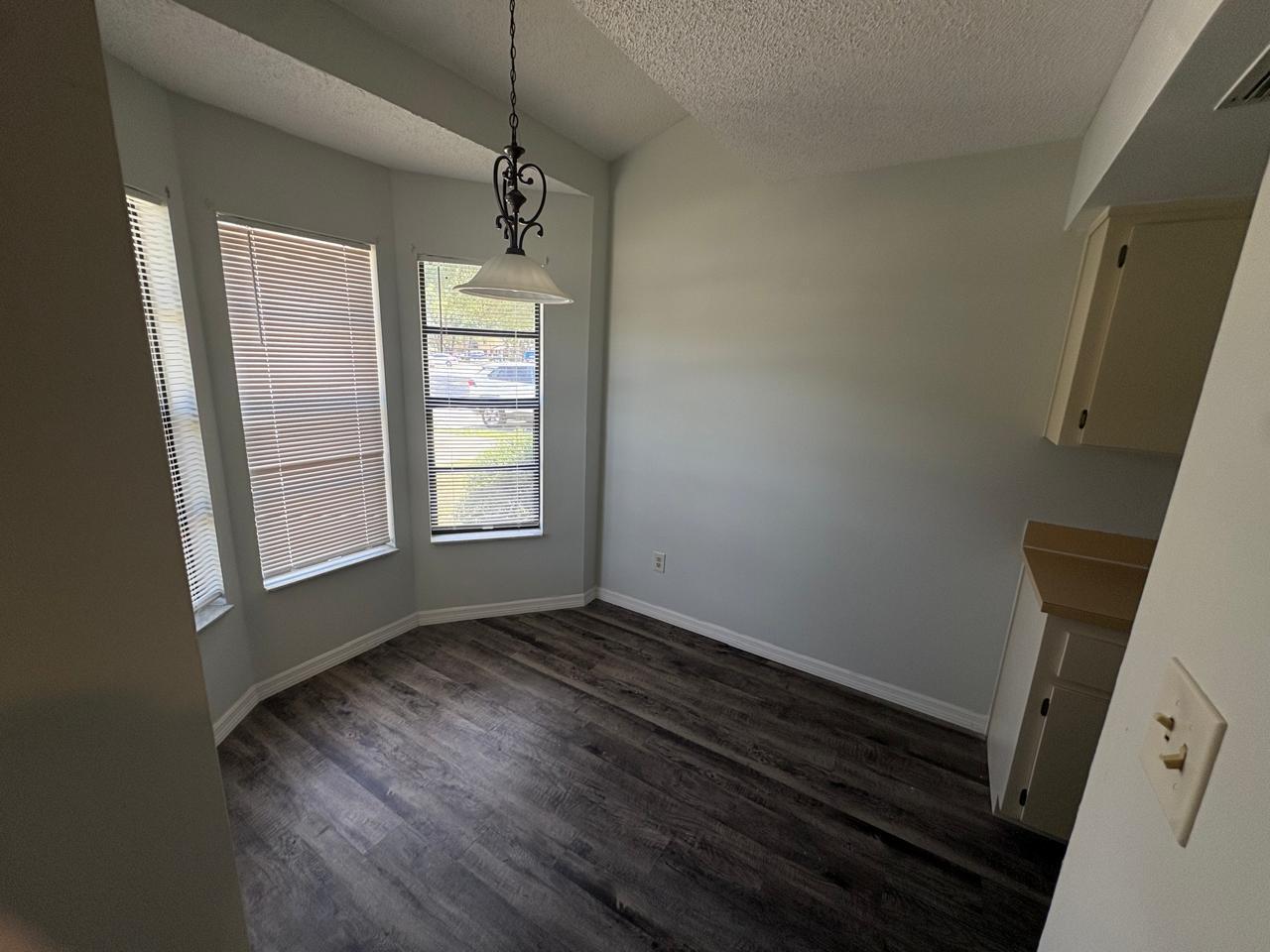 A dining nook with wood-look flooring, a bay window, and a hanging light fixture — 1838 Foxhall Circle, Kissimmee FL 34741, KISSIMMEE, FL