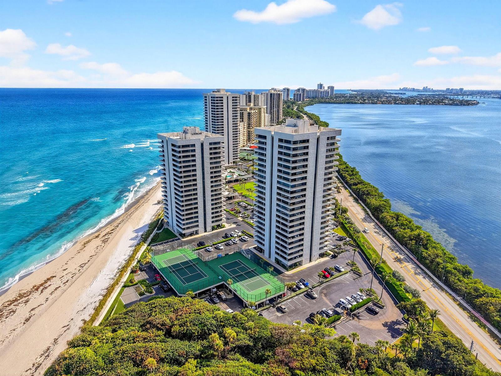 An aerial view shows two high-rise apartment buildings situated between a beach and a bay — 5540 N Ocean Drive # 1c, Singer Island FL 33404, SINGER ISLAND, FL