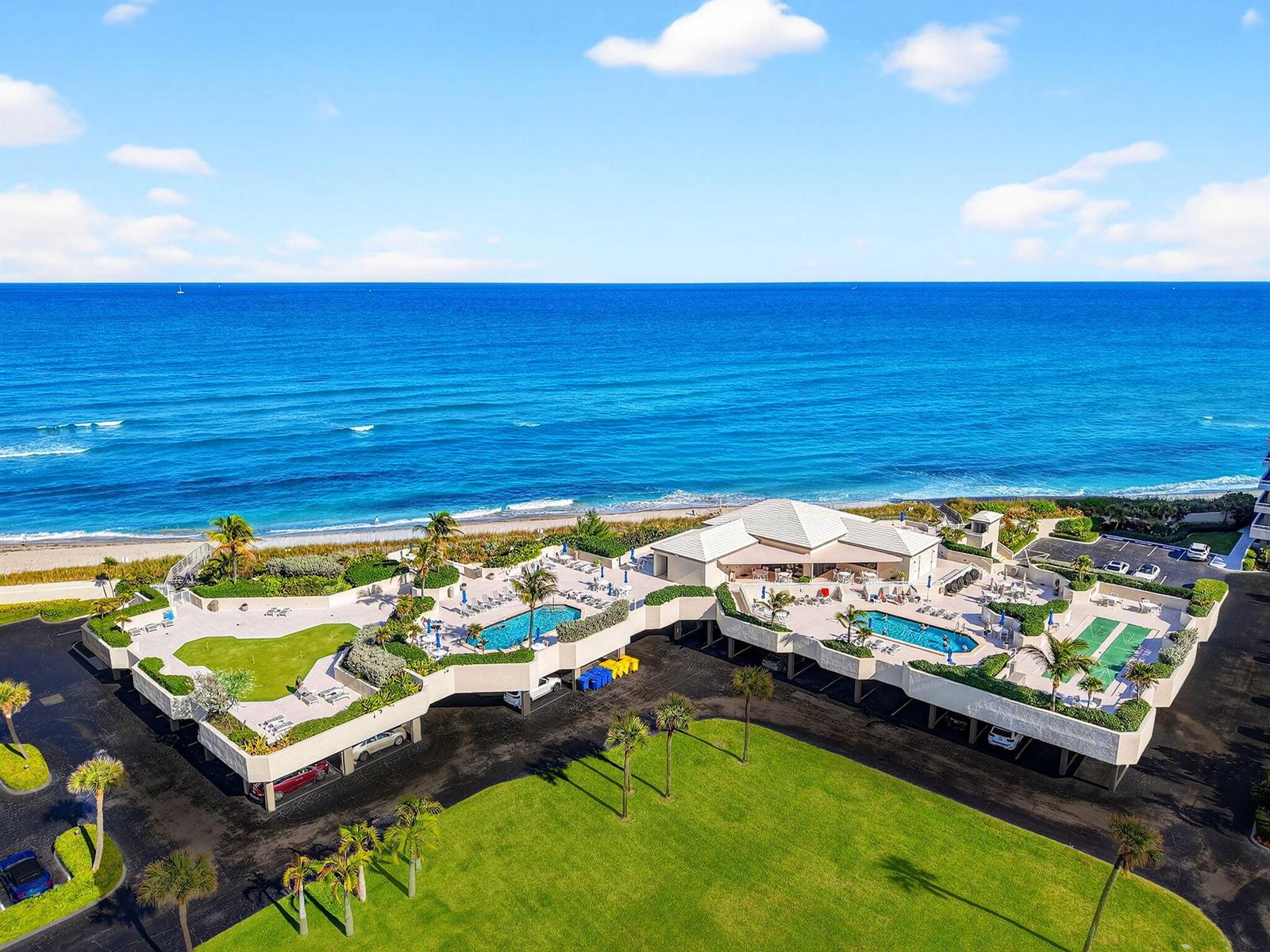 An aerial view shows a beachfront property with two swimming pools and a putting green — 5540 N Ocean Drive # 1c, Singer Island FL 33404, SINGER ISLAND, FL
