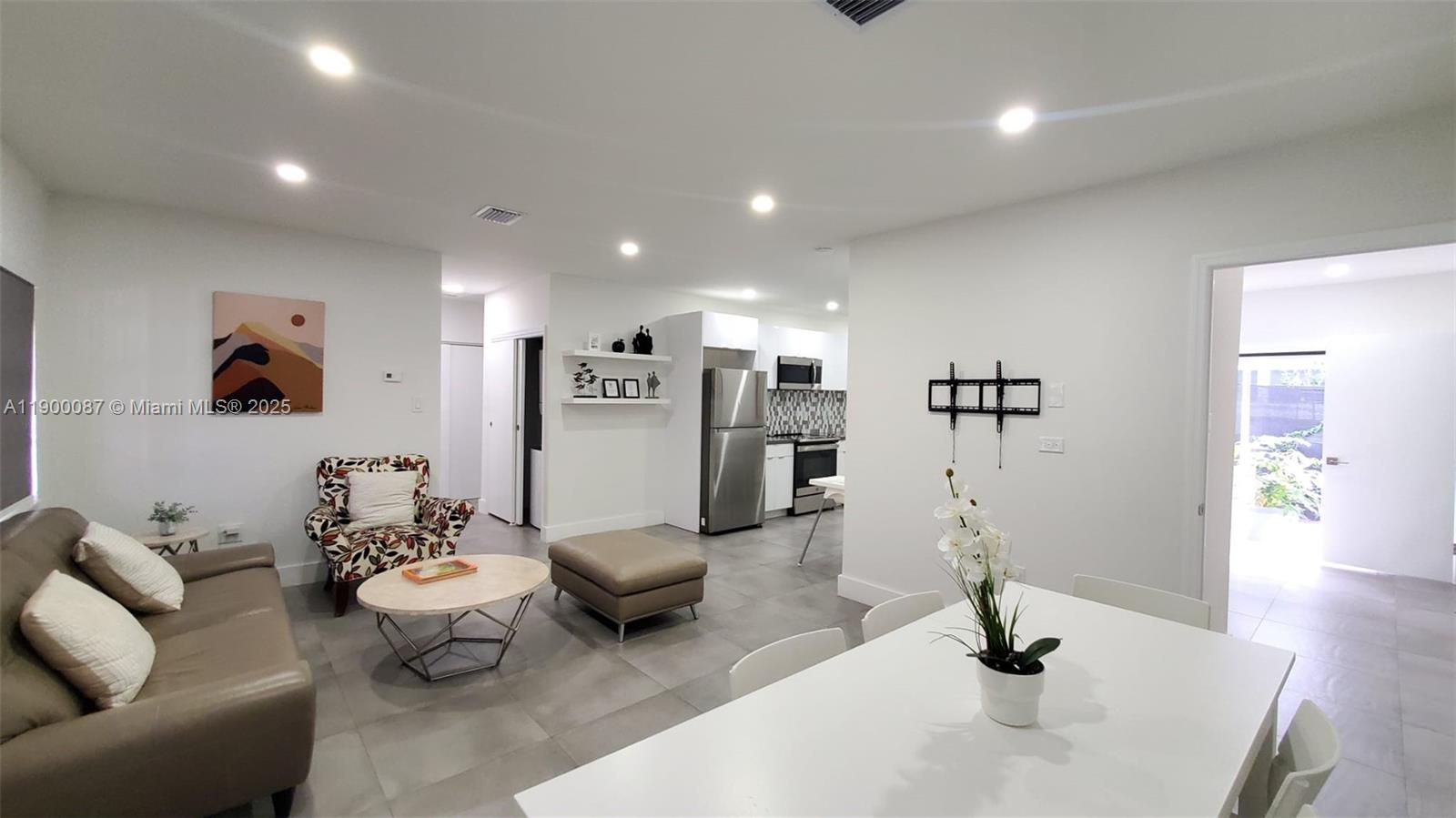 An open-concept living and dining area features light tile flooring and white walls — 510 NE 66th St # 1, Miami FL 33138, MIAMI, FL