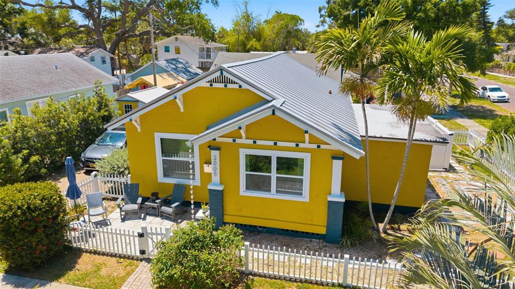A bright yellow bungalow with a metal roof and a small front patio with chairs — 2005 3RD STREET S, ST PETERSBURG, FL