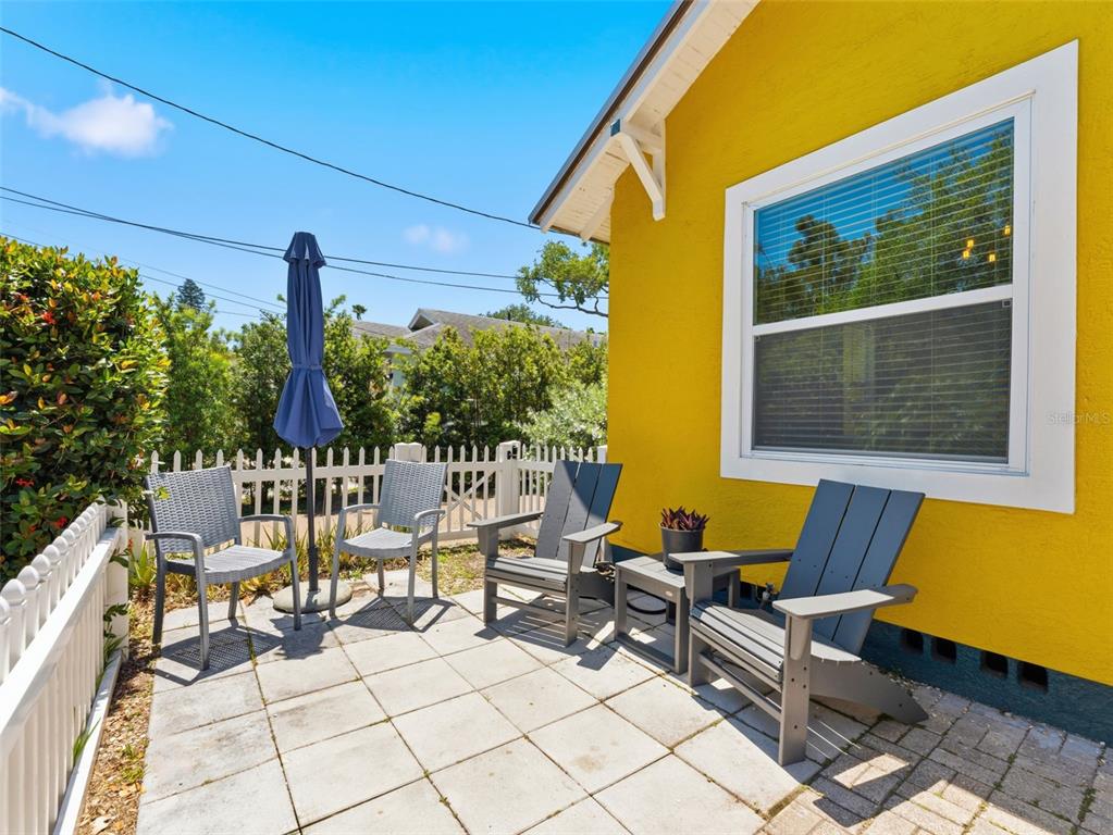 A patio with four chairs and a closed umbrella sits beside a yellow house — 2005 3RD STREET S, ST PETERSBURG, FL