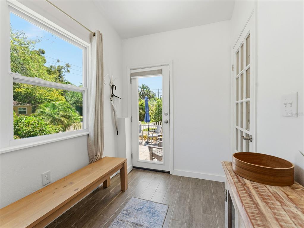 A bright entryway features a wooden bench, a glass-paned door, and wood-look tile flooring — 2005 3RD STREET S, ST PETERSBURG, FL