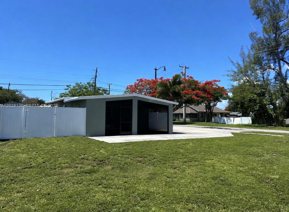 A view of a single-story house exterior with a screened-in patio and white vinyl fencing — 810 NE 3rd Ave, Pompano Beach FL 33060, POMPANO BEACH, FL