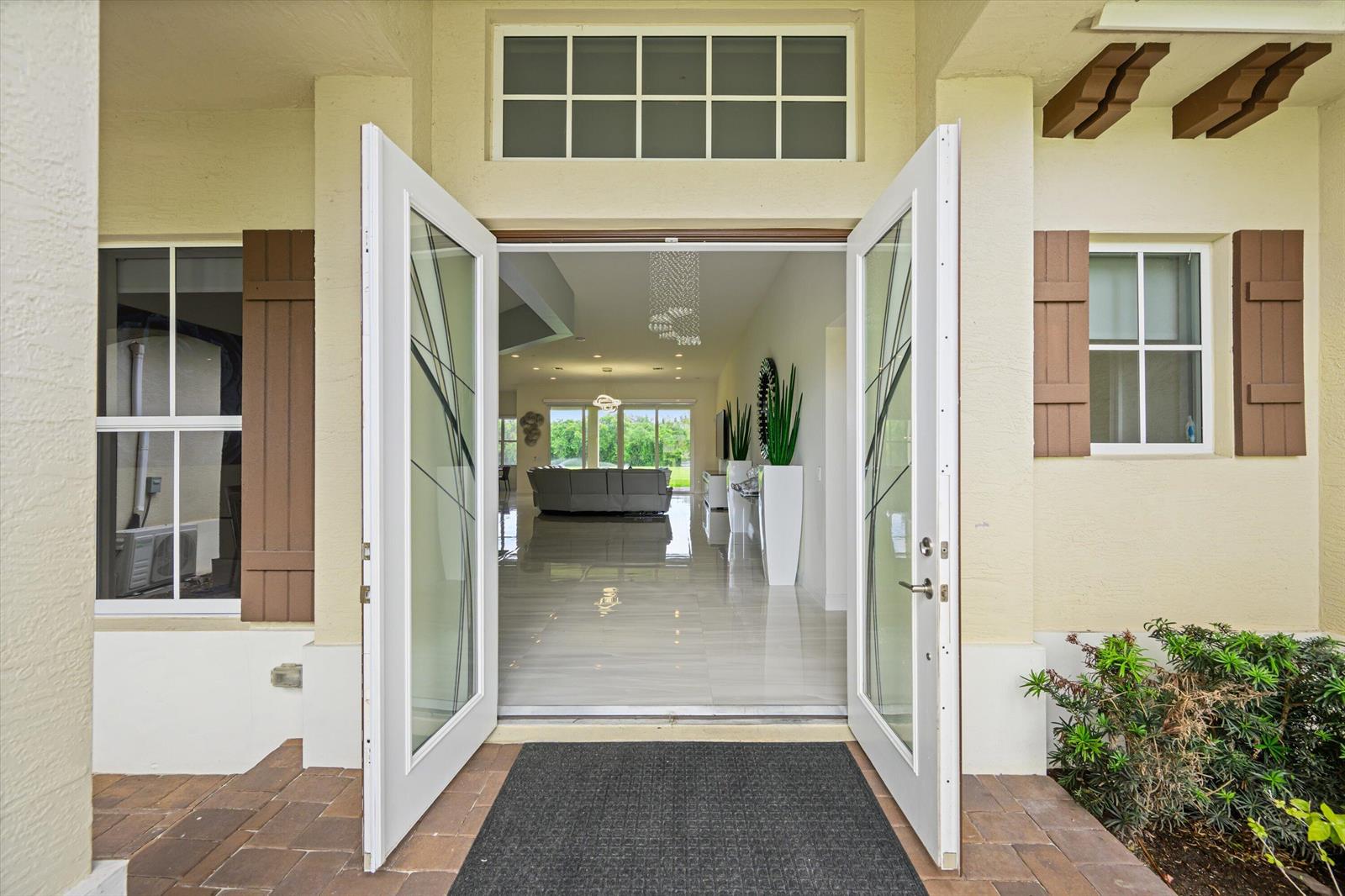 An open double door reveals a bright, tiled living area with a view of the backyard — 7336 Sisken Terrace, Lake Worth FL 33463, LAKE WORTH, FL