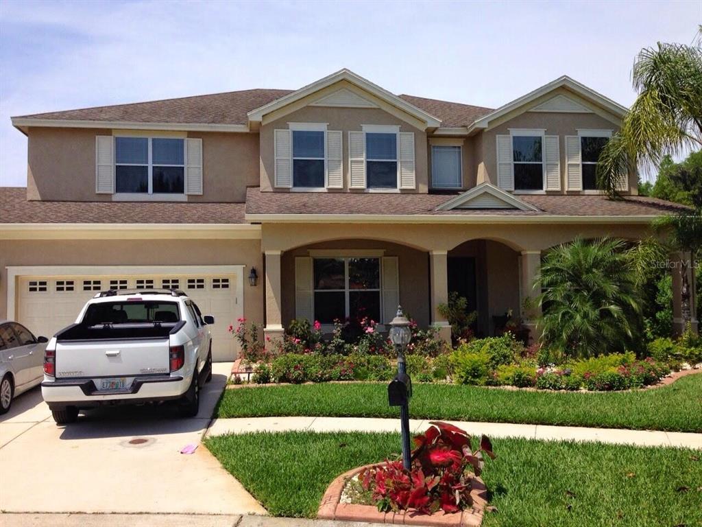 A two-story suburban house with a tan stucco exterior, a two-car garage, and landscaping — 10503 PALM COVE AVENUE, TAMPA, FL