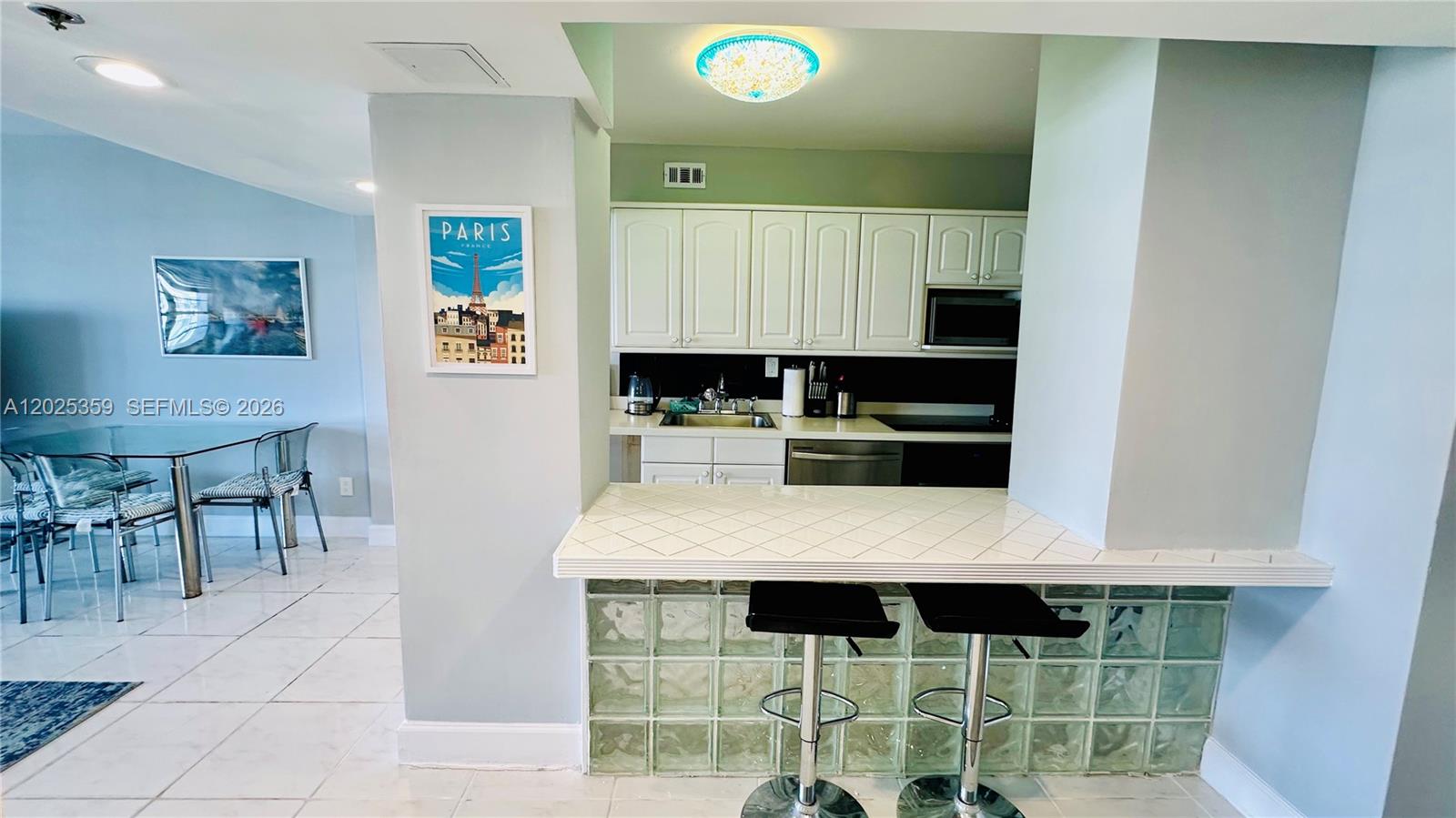 A kitchen features white cabinets, a tiled breakfast bar, and glass block accents — 100 Lincoln Rd # 720, Miami Beach FL 33139, MIAMI BEACH, FL
