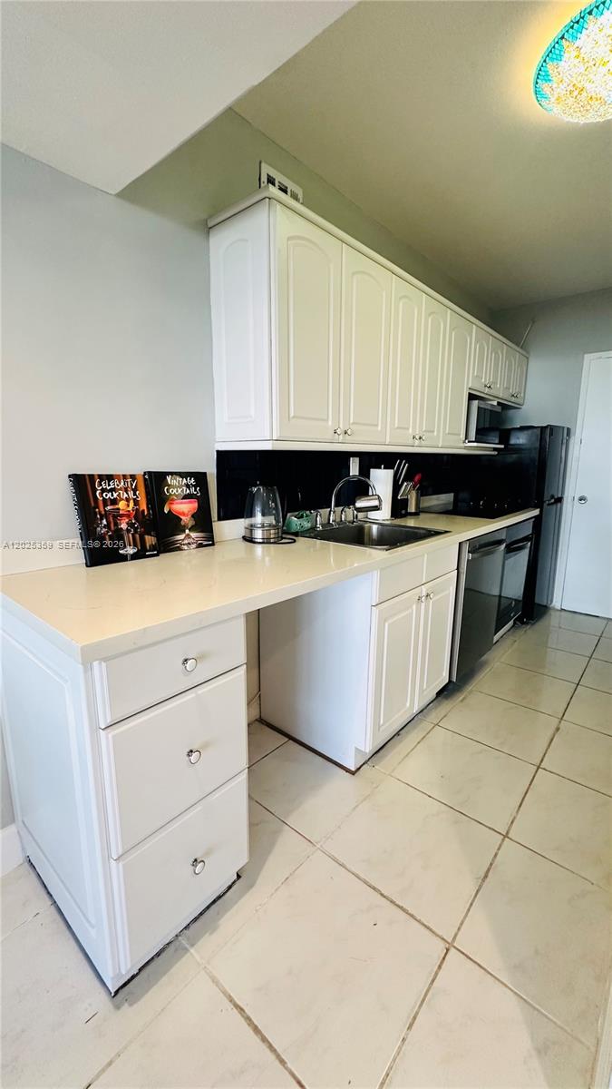 A kitchen features white cabinets, a light countertop, a stainless steel sink, and tile flooring — 100 Lincoln Rd # 720, Miami Beach FL 33139, MIAMI BEACH, FL