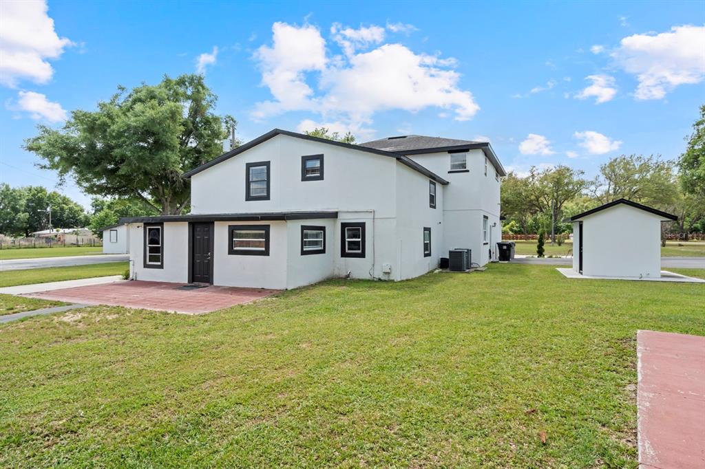 The exterior of a two-story white house with black trim and a detached shed — 2509 APPY LANE, APOPKA, FL