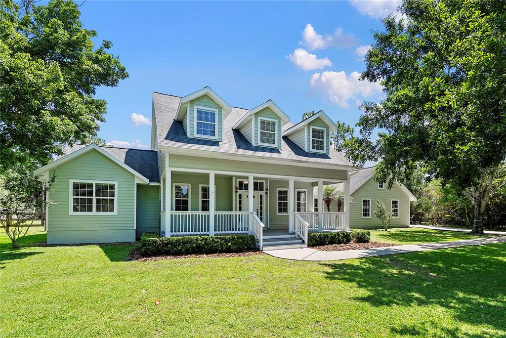 A two-story light green house with a front porch and three dormer windows — 761 N BELFAST PLACE, CHULUOTA, FL