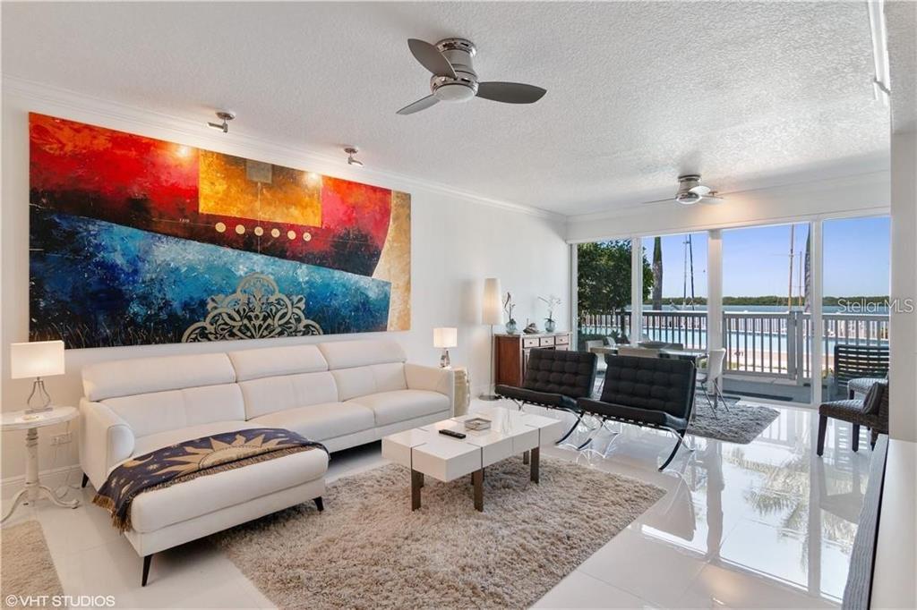 A modern living room features a white sectional sofa, abstract wall art, and waterfront views — 615 DREAM ISLAND ROAD UNIT 107, LONGBOAT KEY, FL