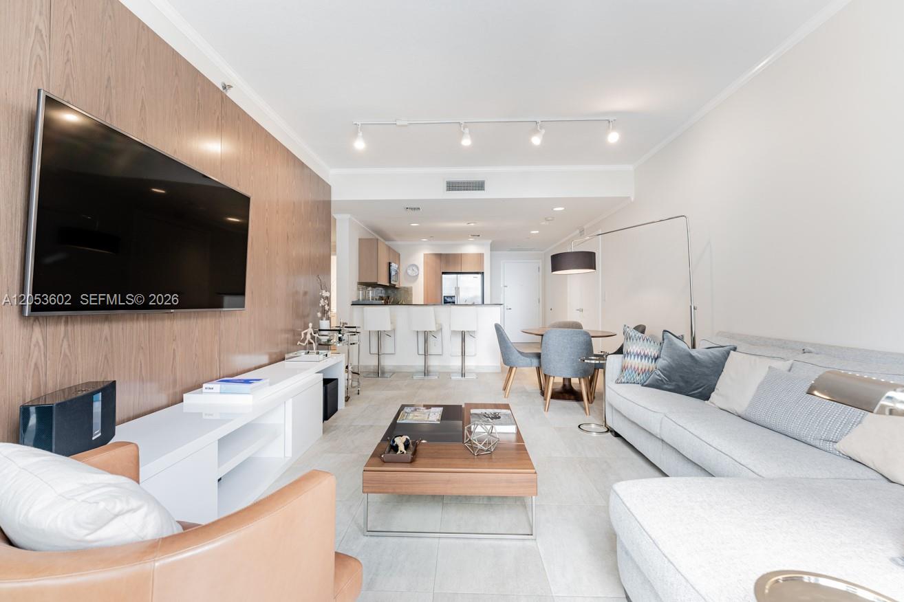 A modern living room features a wood-paneled accent wall, a white media console, and a sectional sofa — 1060 Brickell Ave # 1507, Miami FL 33131, MIAMI, FL