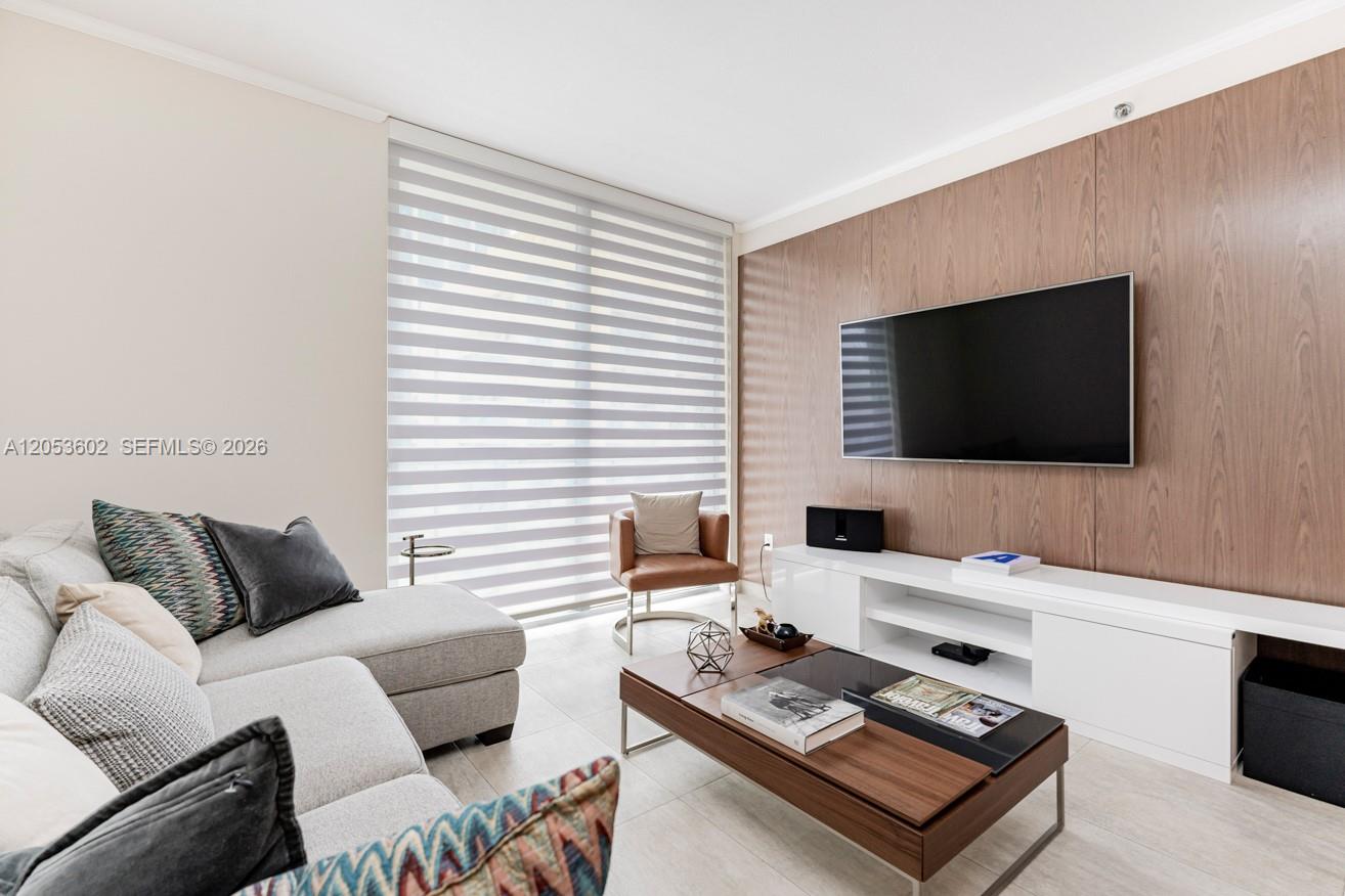 A modern living room features a wood-paneled accent wall, a television, and a sectional sofa — 1060 Brickell Ave # 1507, Miami FL 33131, MIAMI, FL