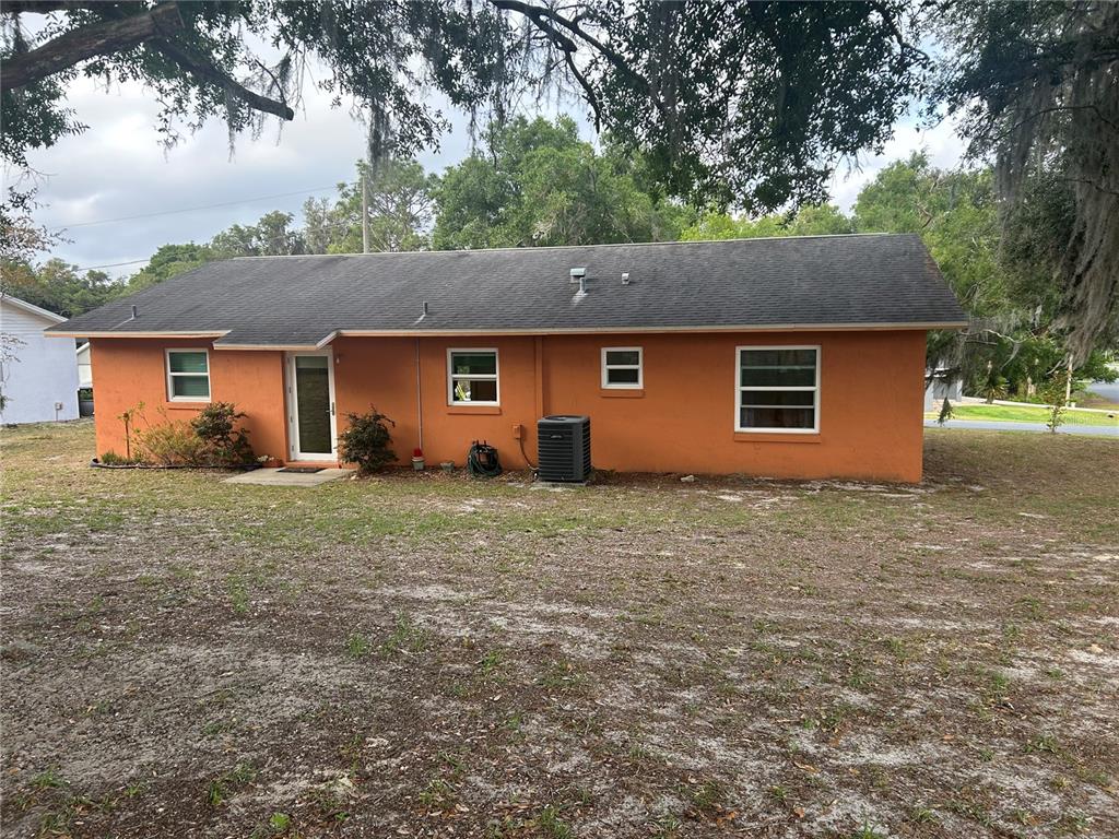 The exterior of a single-story orange house features a dark shingled roof and several windows — 3 JUNIPER PASS LANE, OCALA, FL