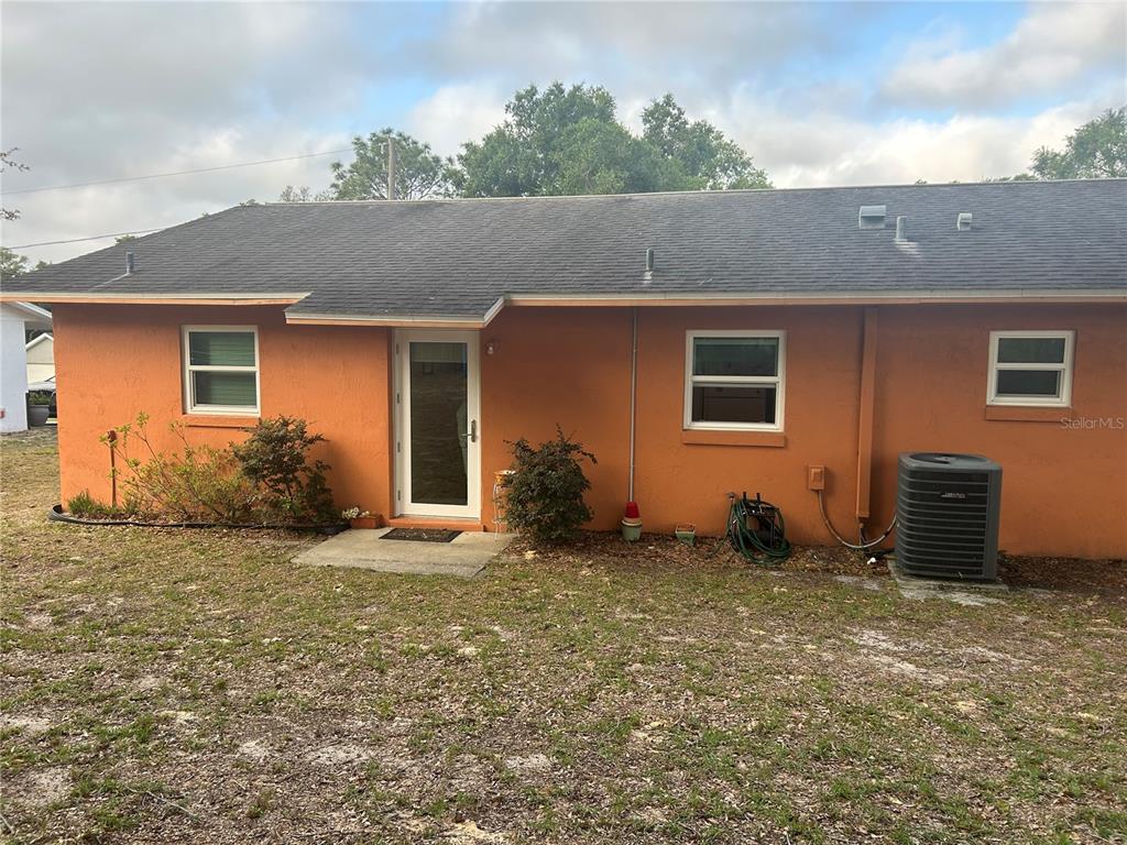The exterior of an orange, single-story house features a glass door and an air conditioner — 3 JUNIPER PASS LANE, OCALA, FL