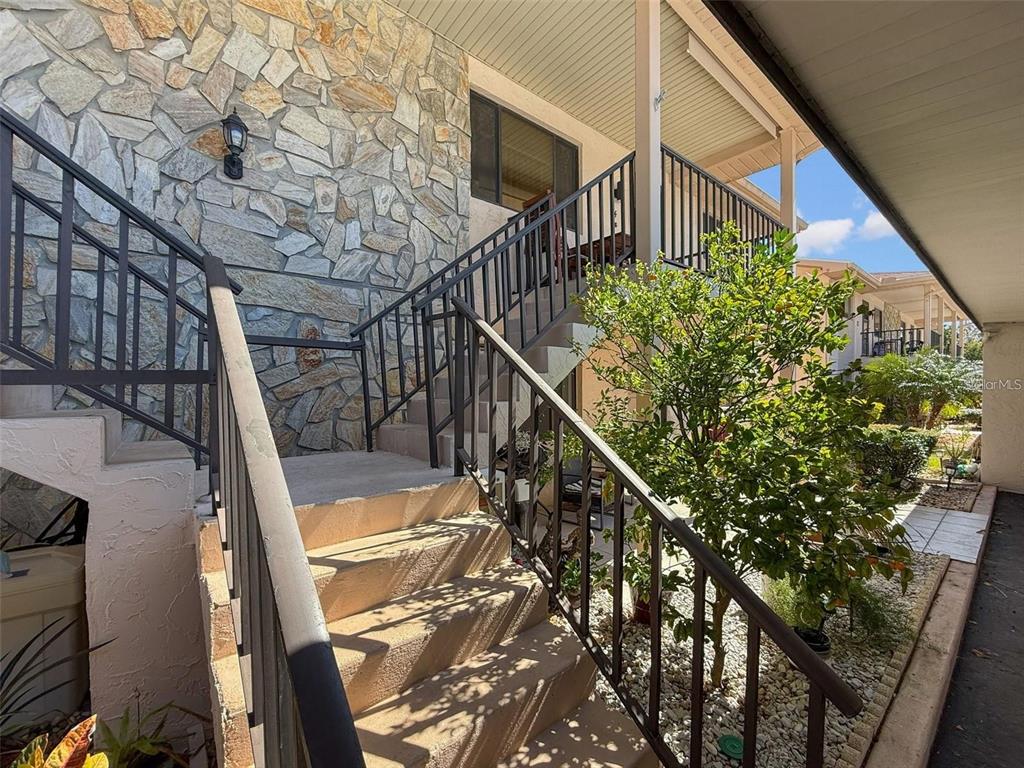 Exterior concrete stairs with black metal railings lead up to a stone-faced building entrance — 9981 EAGLES PT CIRCLE UNIT 4, PORT RICHEY, FL