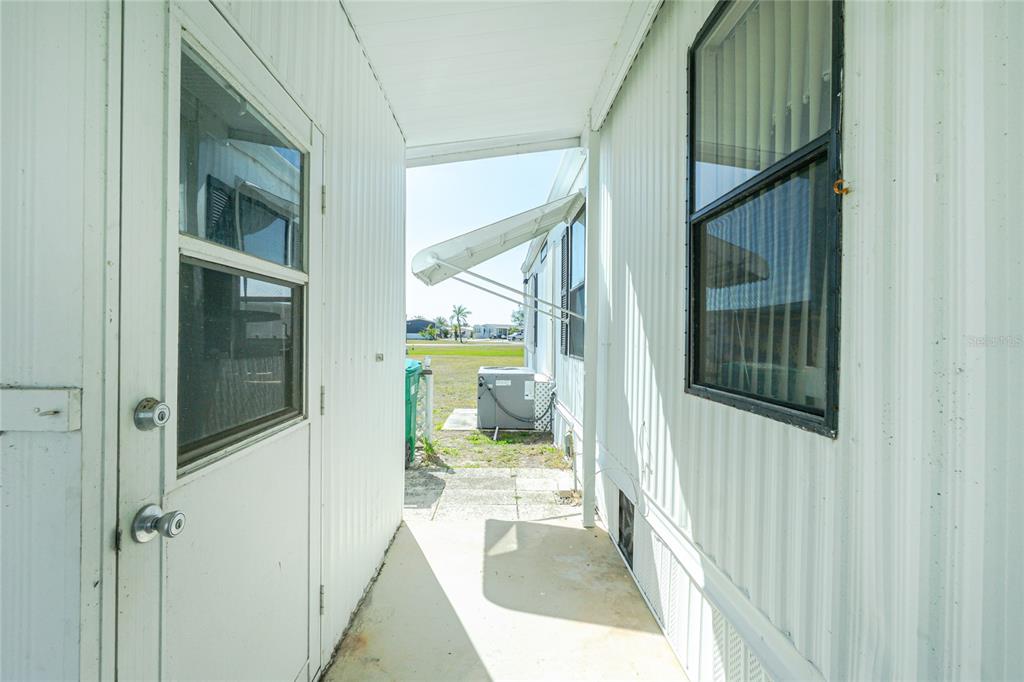 A narrow outdoor walkway between two mobile home sections leads to a small backyard area — 7369 CANDACE LANE, PORT CHARLOTTE, FL